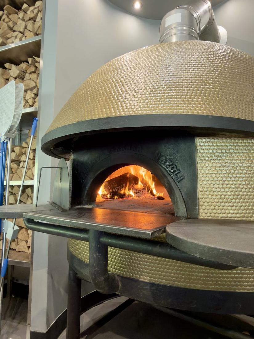 Wood-fired pizza oven with open flames